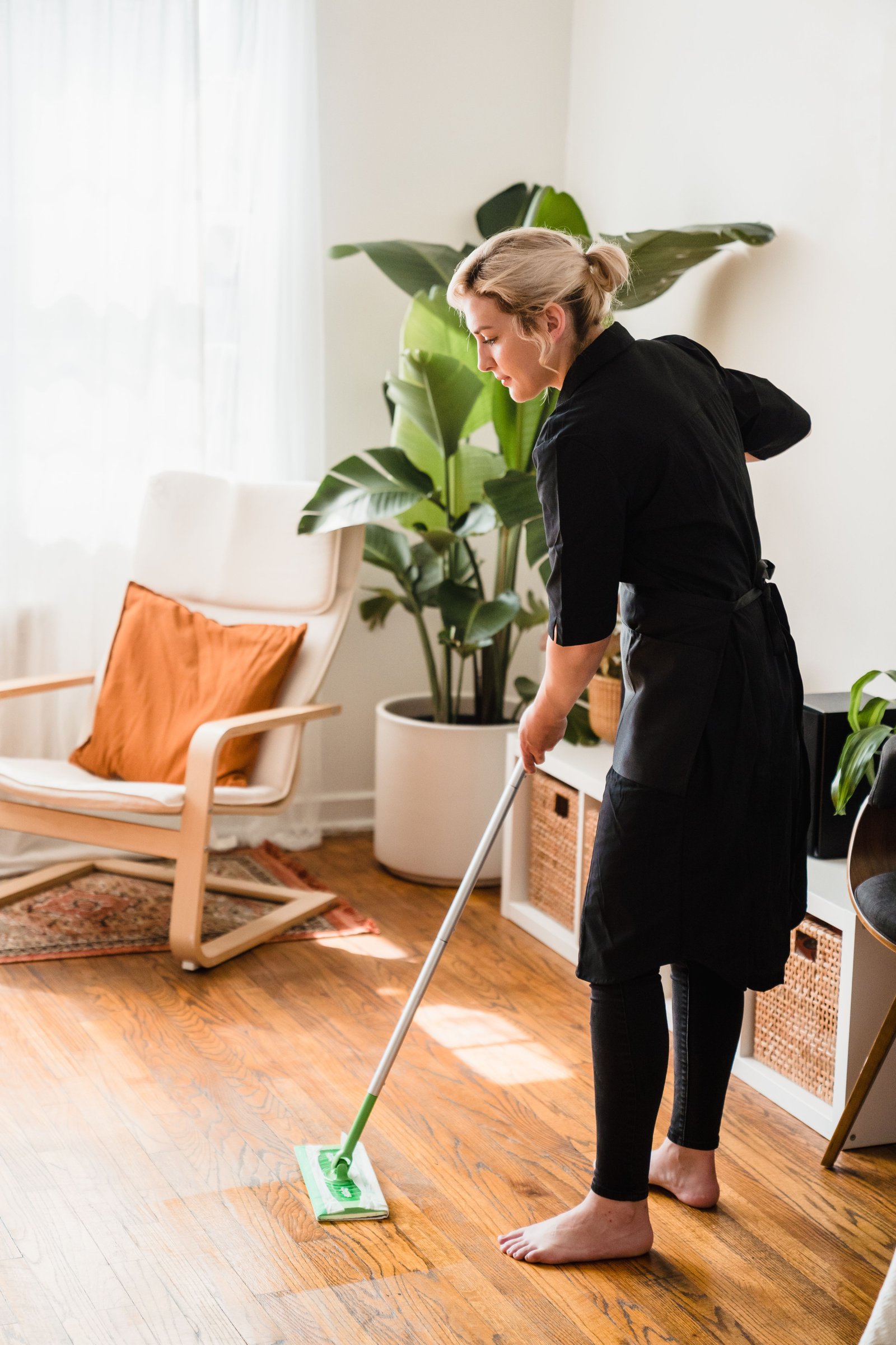 Cleaner sweeping a bright residential living room